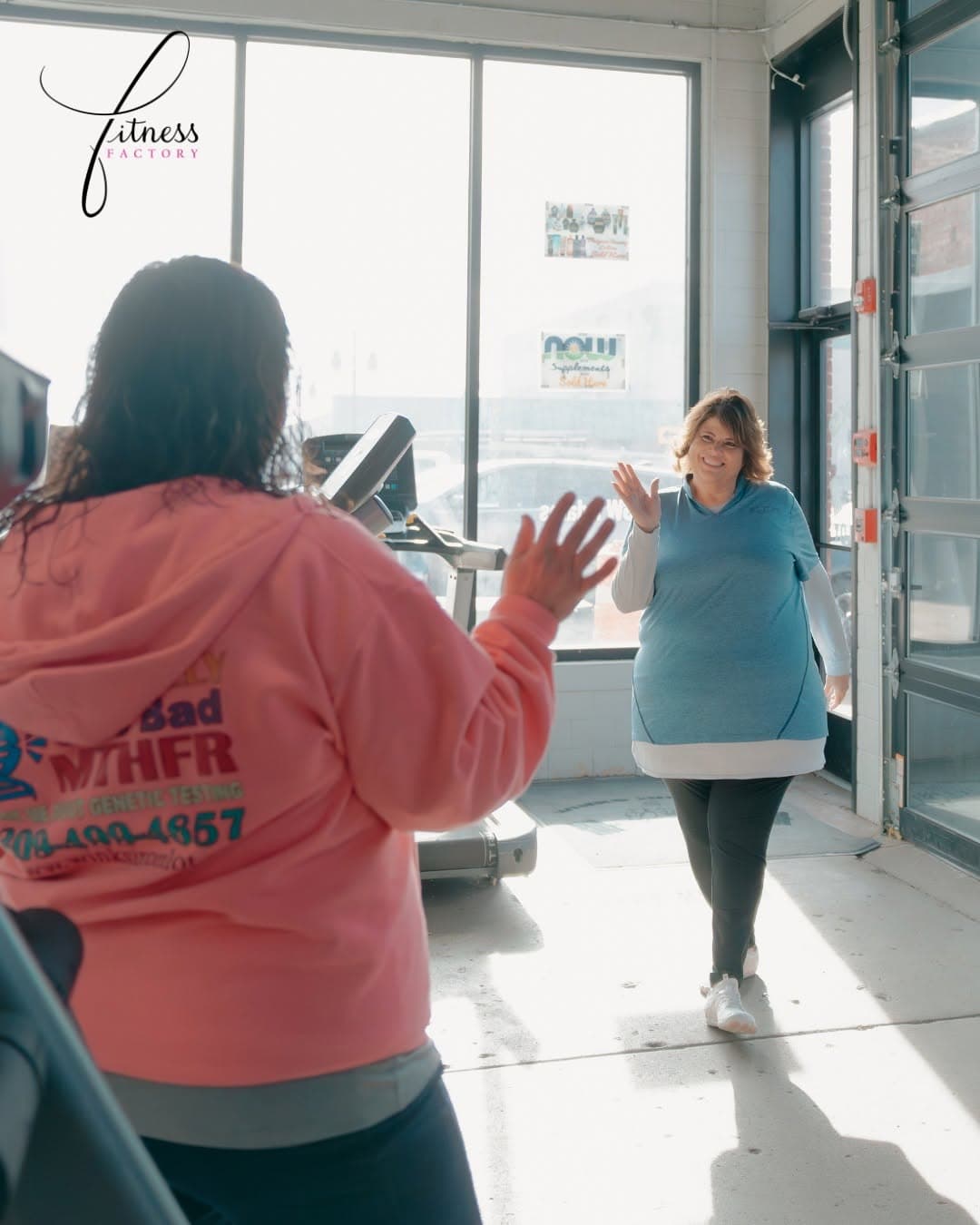 Trainer in a Bad MTHFR Genetic Testing hoodie greeting a client arriving at the gym